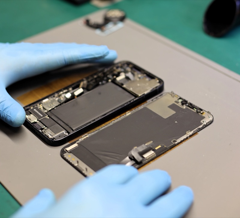 Handy-Reparatur bei KM Elektronik Recklinghausen: iPhone mit geöffnetem Display auf dem Werkstatt-Tisch